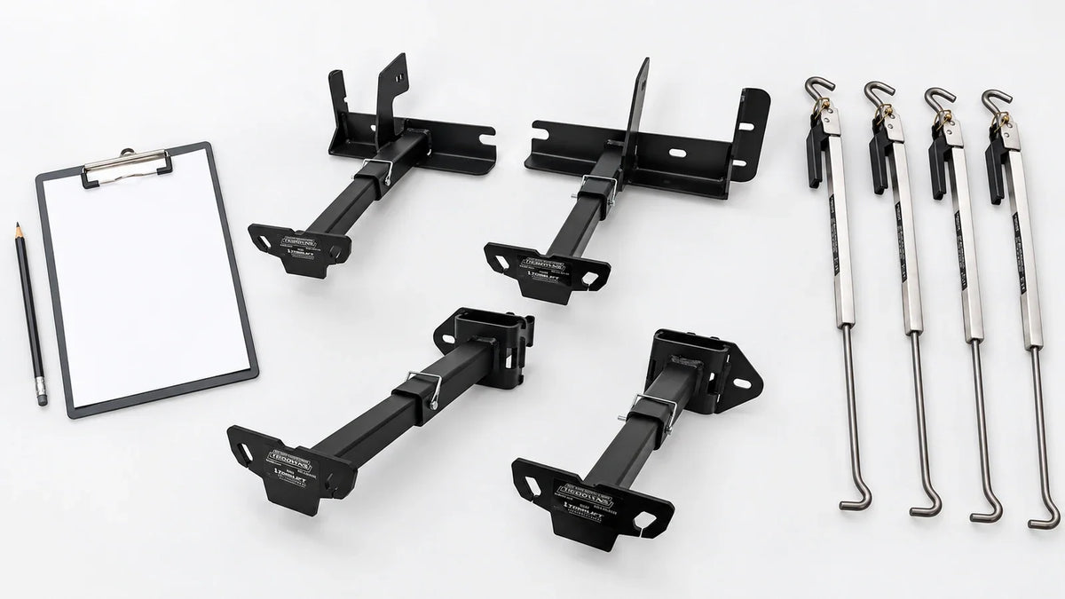 Front and rear TorkLift tie-down pairs, four polished FastGun turnbuckles, and a blank clipboard with a pencil on a light background.