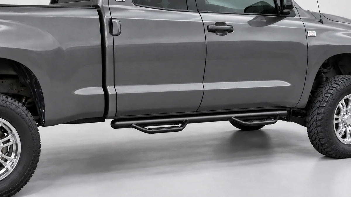 Black tubular cab-length running board beneath a graphite pickup, ending before the bed.